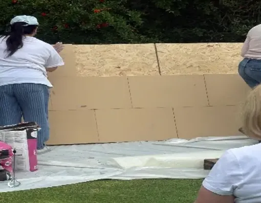 Homeowners fixing wood fibre panels to the mock wall