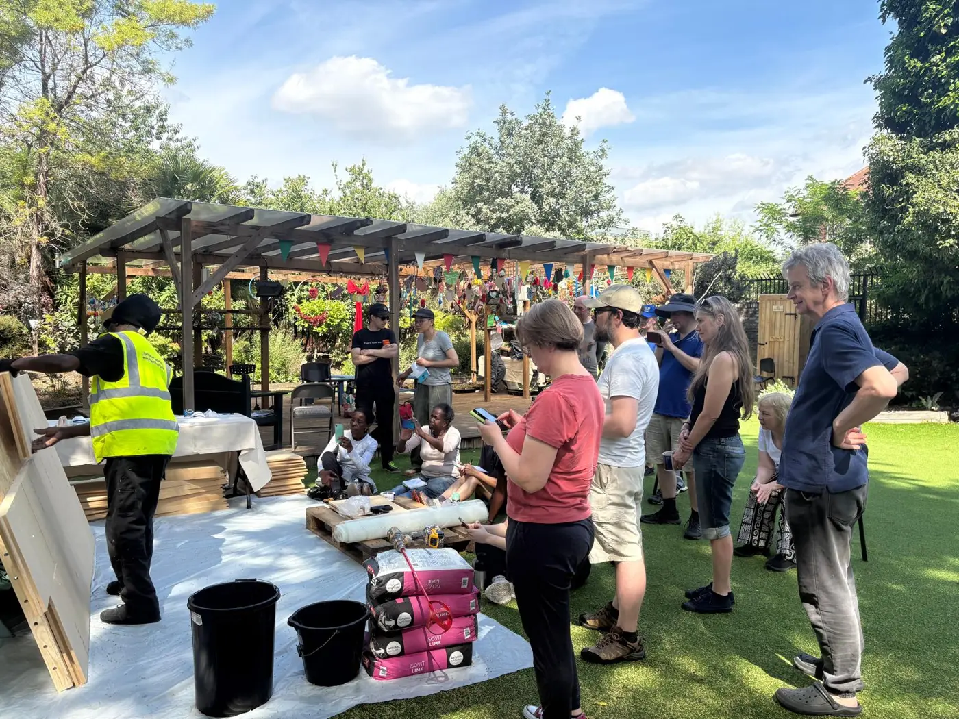 Homeowners gathered round as the team shows how the wood fibre and lime wall goes together, Besson Street Community Garden
